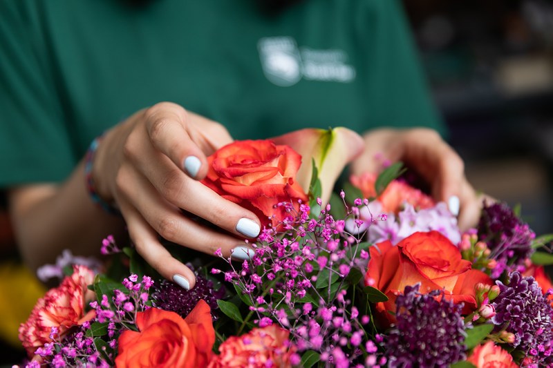 Detailansicht Lernende Floristin beim Blumenstrauss schmücken mit Rose