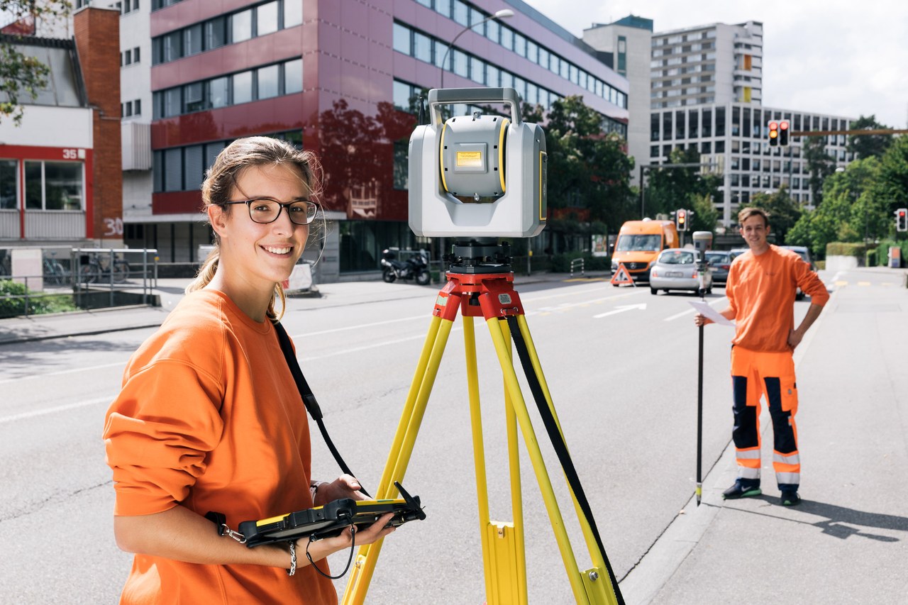 Lernende und Lernender Geomatik beim Vermessen mit Theodolit