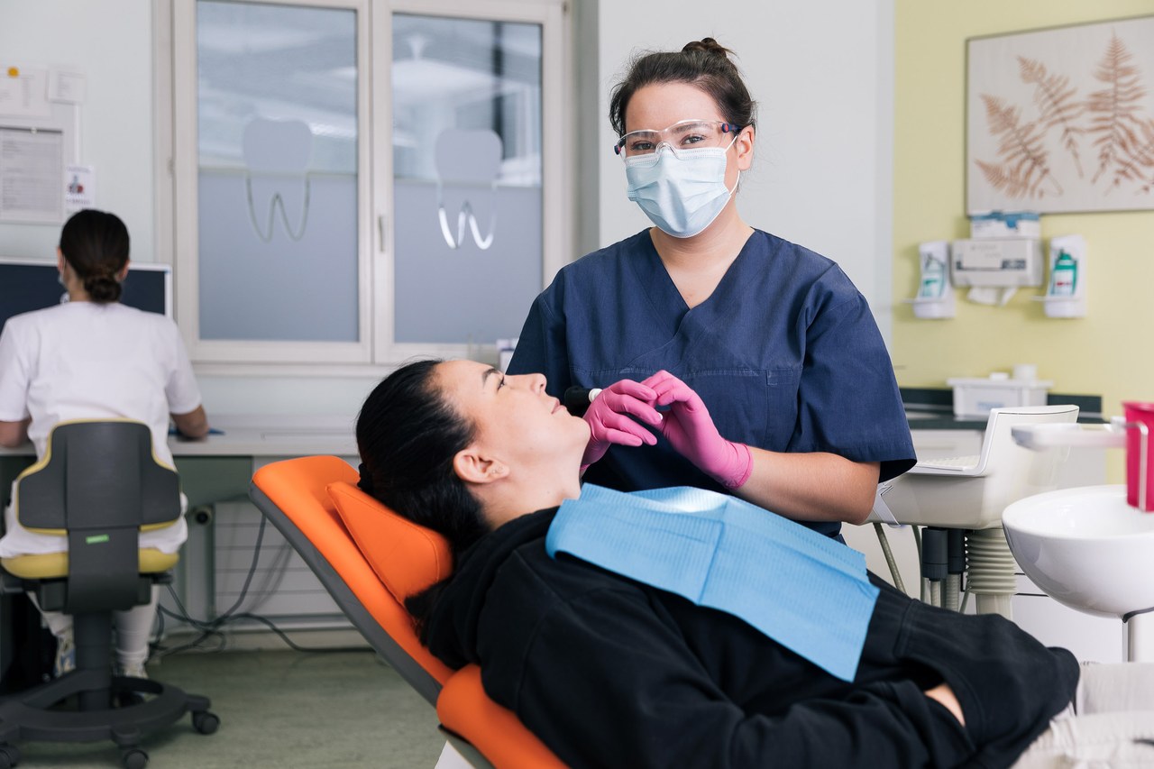 Lernende Dentalassistentin beim Vorbereiten einer Patientin
