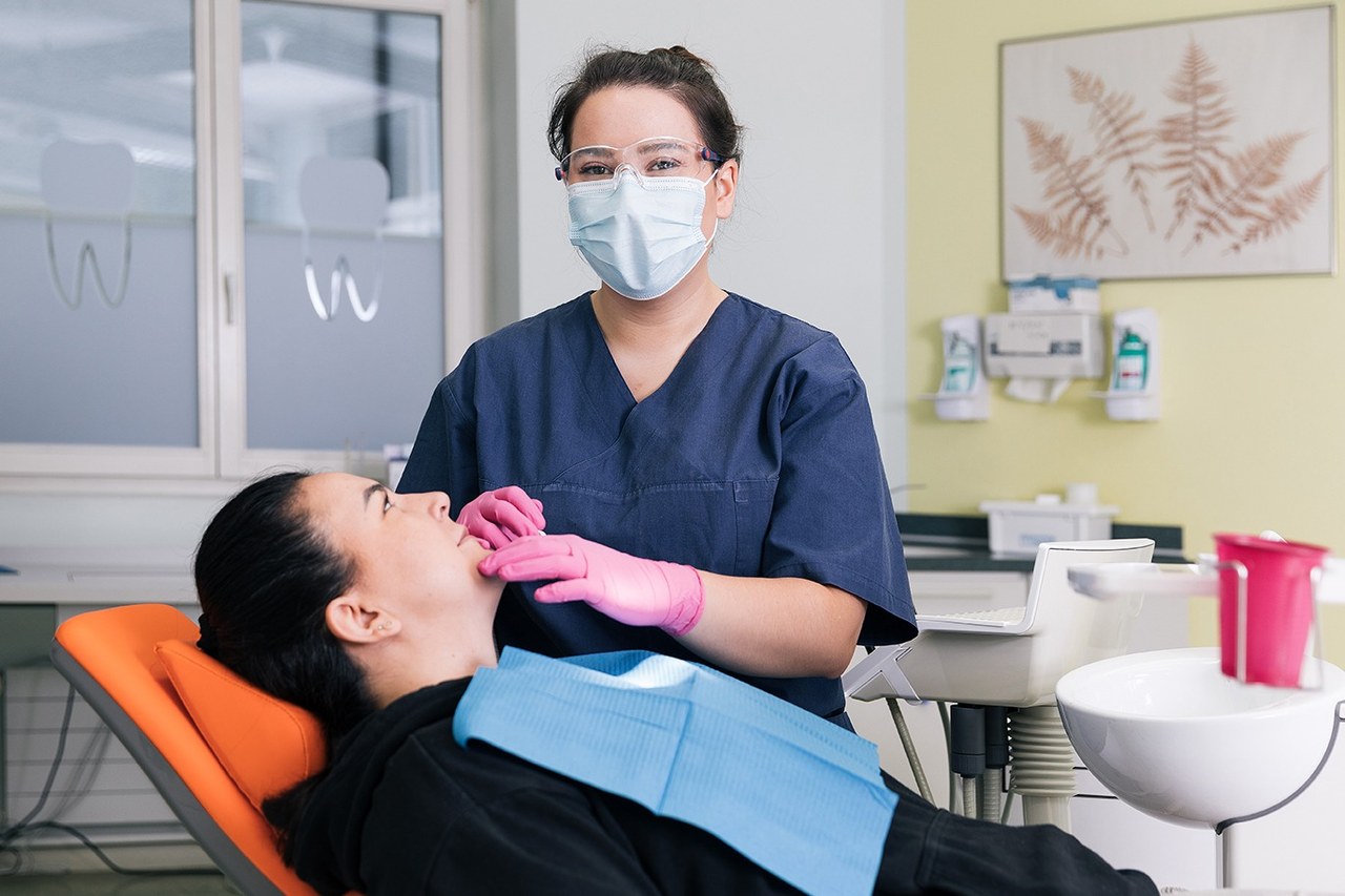 Lernende Dentalassistentin beim Vorbereiten einer Patientin