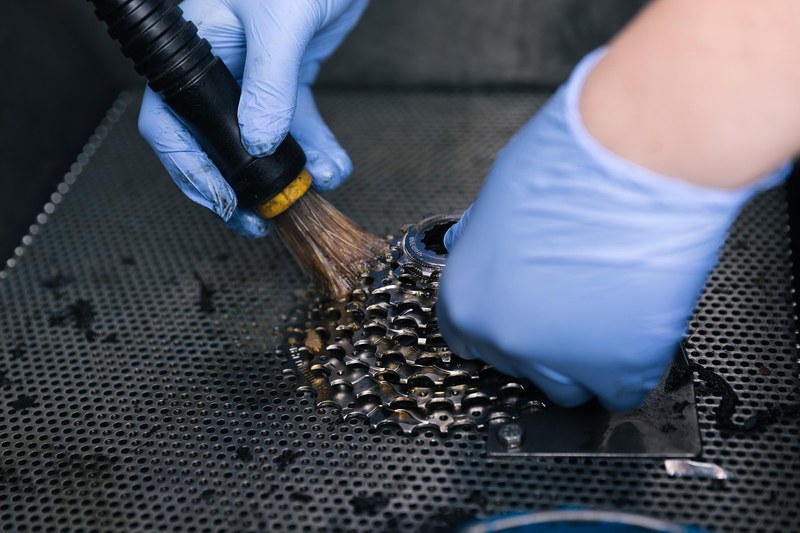 Detailbild Lernende Fahrradmechanikerin beim Putzen einer Kassette