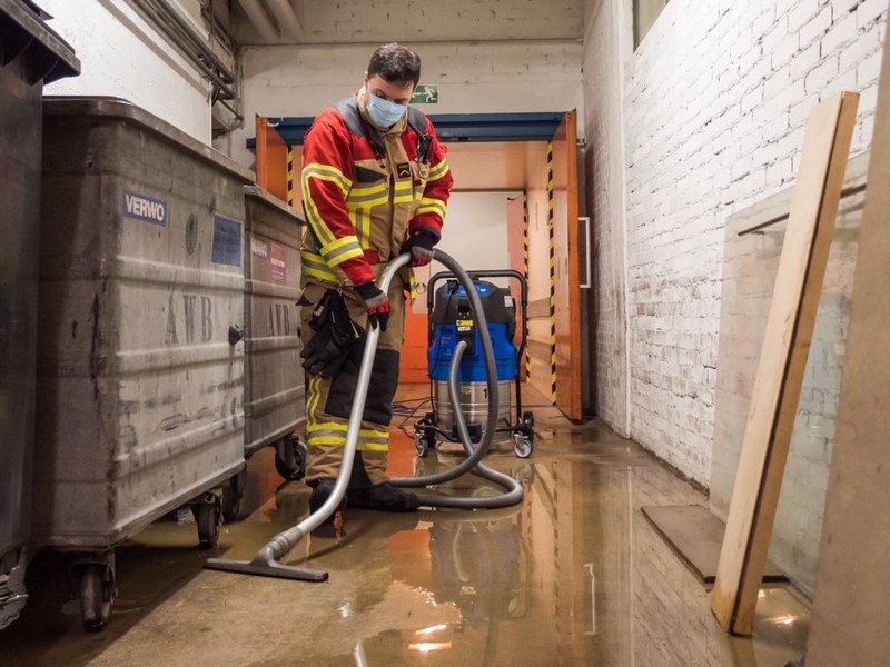 Angehöriger der Milizfeuerwehr mit Wassersauger