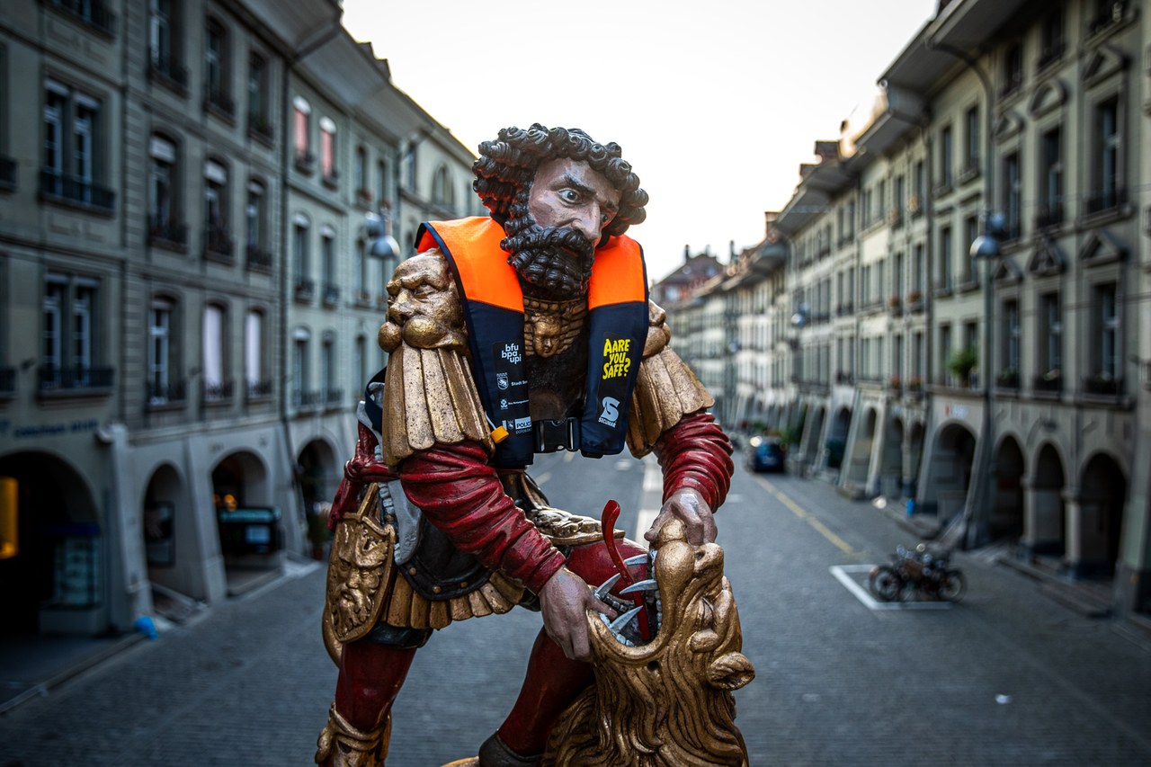 Das Bild zeigt die Figur des Simsonbrunnen mit einer kleinen, orangen Rettungsverste um den Nacken.