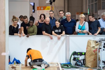 Impressionen von den SwissSkills 2018 in Bern: Zuschauerinnen und Zuschauer beobachten einen jungen Mann, der auf dem Boden kniend einen Wettkampf bestreitet.. Vergrösserte Ansicht