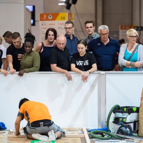 Impressionen von den SwissSkills 2018 in Bern: Zuschauerinnen und Zuschauer beobachten einen jungen Mann, der auf dem Boden kniend einen Wettkampf bestreitet.