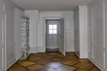 Rathausgasse 12: Gassenzimmer im zweiten Obergeschoss mit ursprünglicher Raumausstattung und Keramikofen von Peter Gnehm. (© Dominique Uldry). Vergrösserte Ansicht