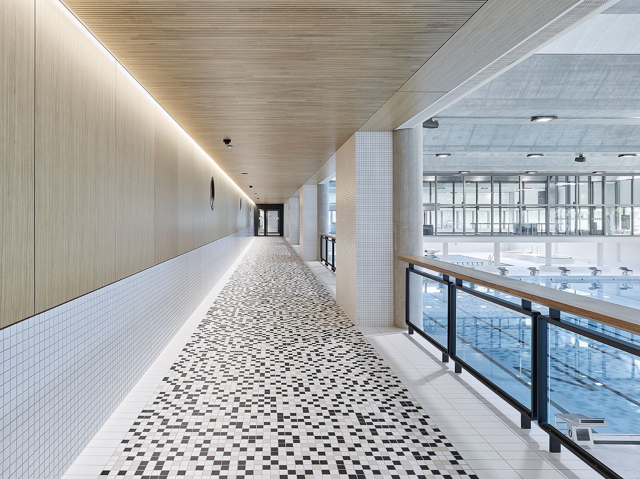 Das Bild zeigt die Galerie der Schwimmhalle, am rechten Bildrand ist das grosse, 50m lange Schwimmbecken zu sehen.