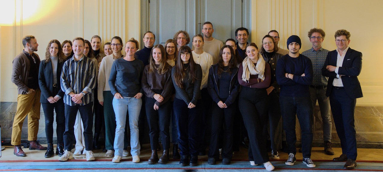 Zahlreiche Menschen stehen nebeneinander in einem Raum.