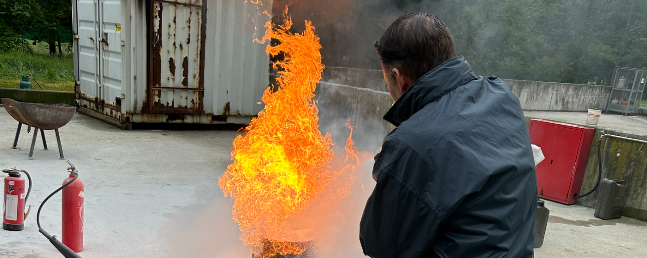 Eine Person löscht ein Feuer mit dem Handfeuerlöscher