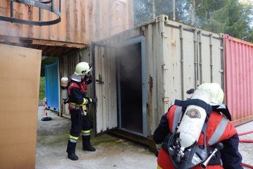 Angehörige der Feuerwehr vor dem Brandcontainer der Heissausbildungsanlage Bern. Vergrösserte Ansicht