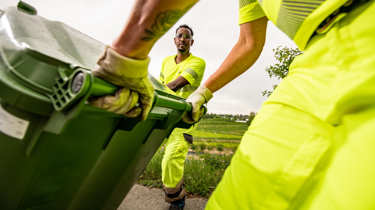 Mitarbeitende rollen Grüngutcontainer zum Kehrichtwagen