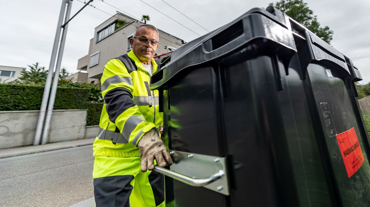 Ein Mitarbeitender steht neben einem Container