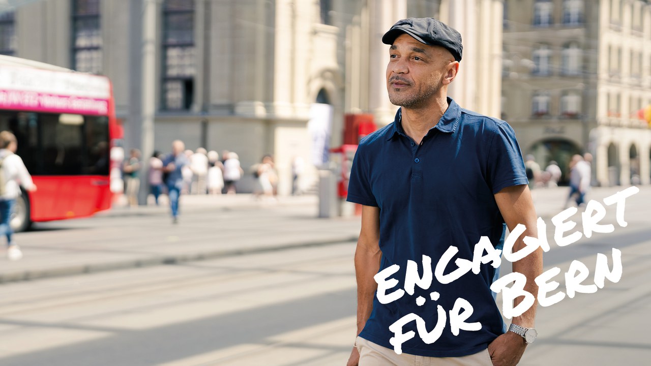Mann in Poloshirt und mit Schirmmütze geht unter dem Berner Baldachin, im Hintergrund ein Bus. Text im Bild: "Engagiert für Bern"