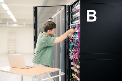 Mann arbeitet an Serverrack mit vielen Kabeln