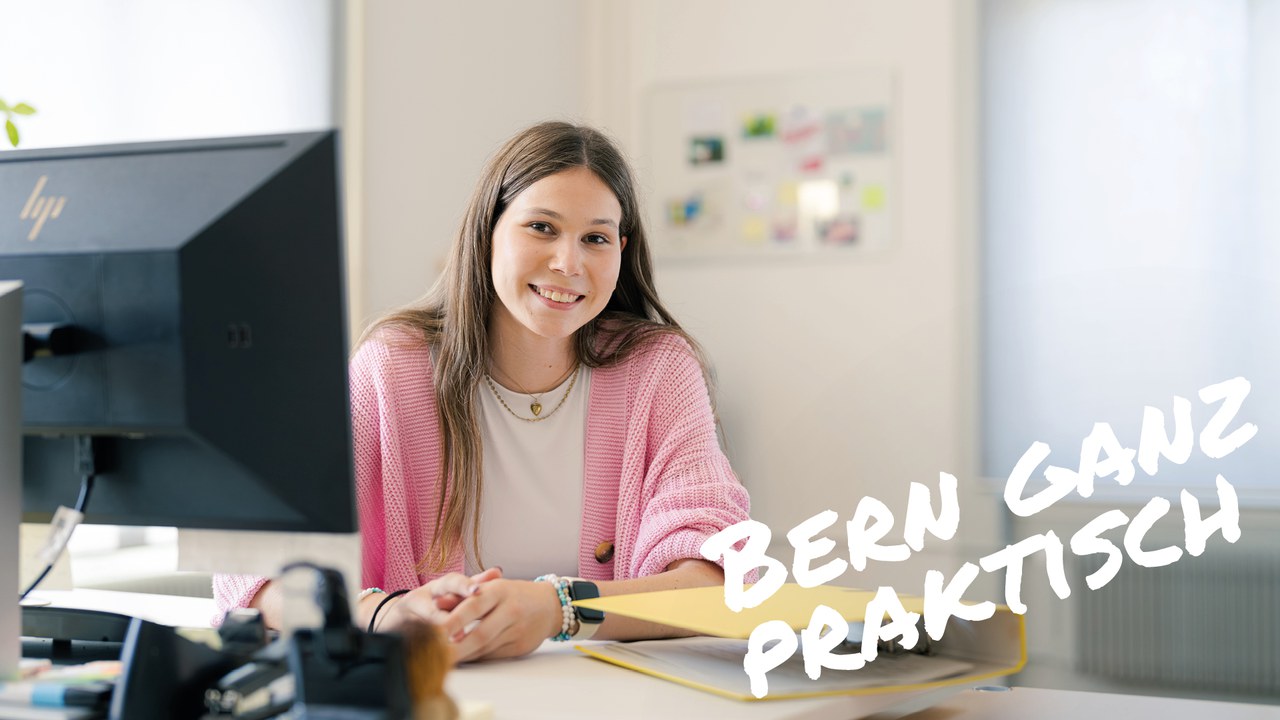Junge Frau sitzt lächelnd an einem Schreibtisch. Text im Bild: "Bern ganz praktisch"