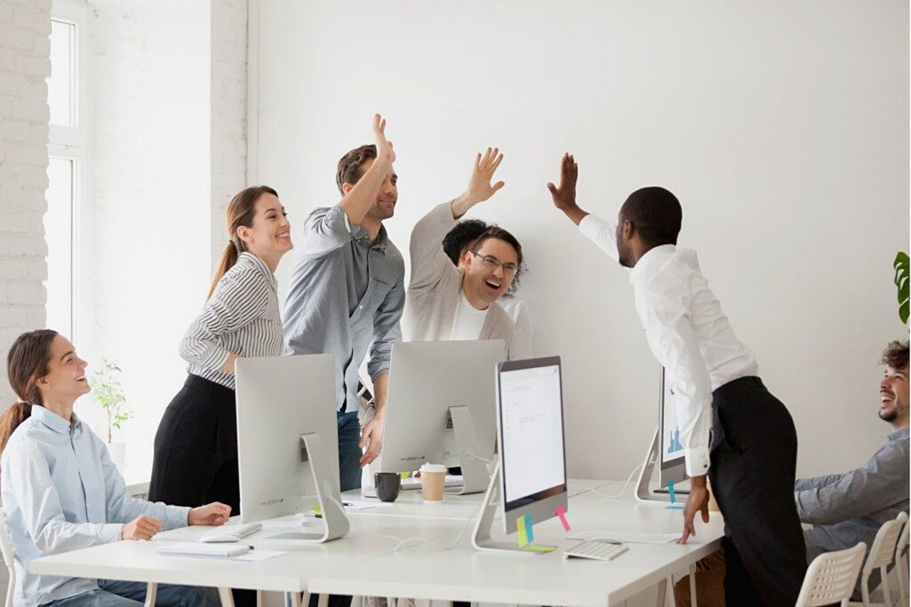 Symbolbild Zusammenarbeit: Arbeitnehmende klatschen sich ab