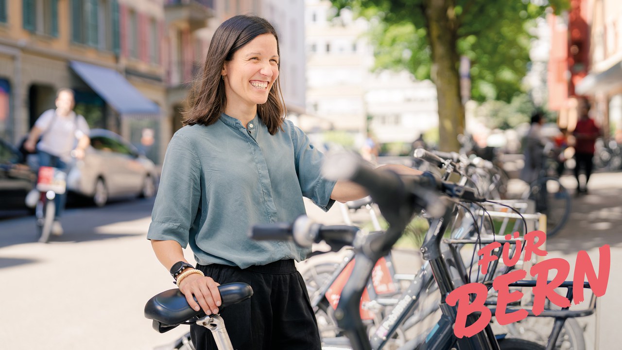 Eine frau steht lachend an ihrem Fahrrad.