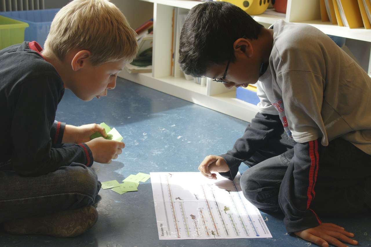 Zwei Buben im Schulzimmer. Sie lösen gemeinsam eine Aufgabe.