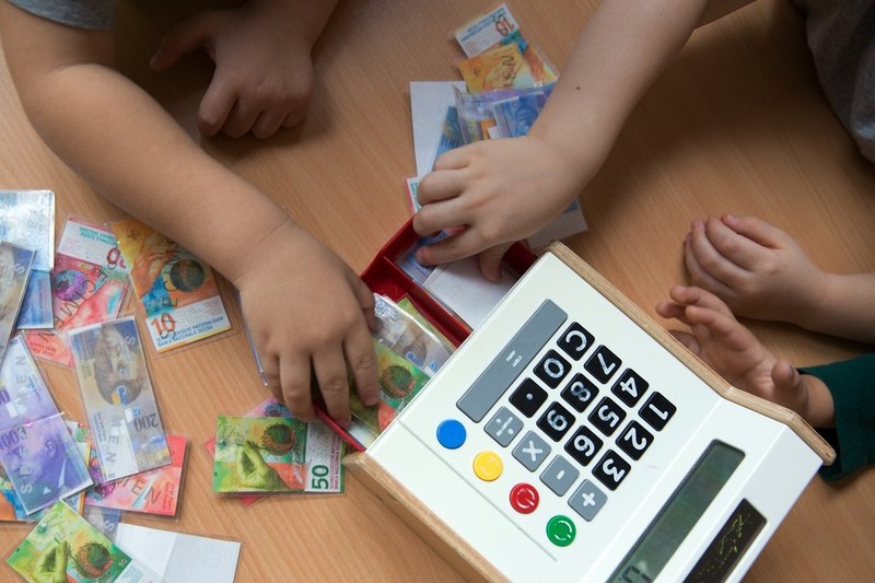 Kinder spielen mit Spielzeugkasse und -geld