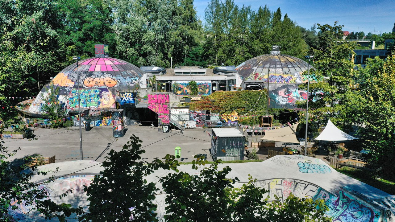 Das Foto zeigt die beiden bunt verzierten Kuppeln des Gaskessels; am unteren Bildrand ist ein Teil der Skater-Anlage zu sehen.