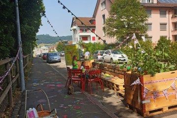 Stühle und Bänke umgeben von Hochbeeten an der Mittelholzerstrasse. Vergrösserte Ansicht