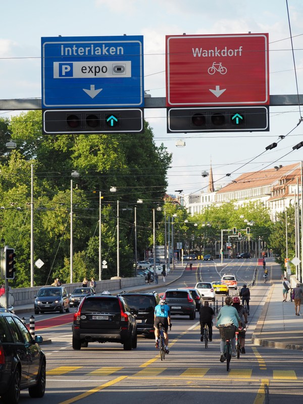 Das Bild zeigt die stark befahrene Lorrainebrücke mit der neu erstellten Velospur stadtauswärts. Im oberen Bildteil ist die Signalisation der Velohauptstrasse mit einer roten Tafel erkennbar.